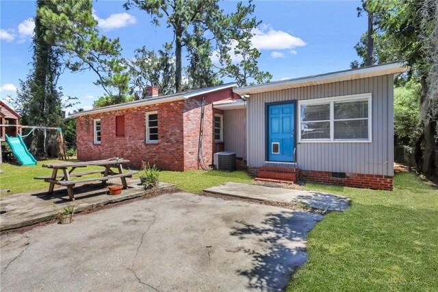 view of front of house featuring a patio, a playground, central AC unit, and a front lawn