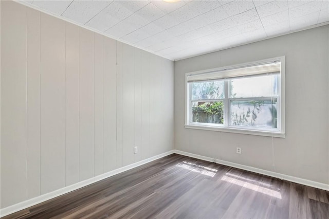 unfurnished room featuring dark hardwood / wood-style floors and wooden walls