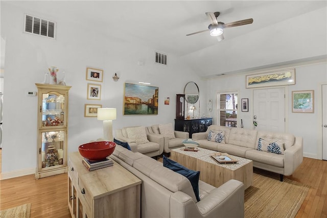 living room with ceiling fan, vaulted ceiling, and light wood-type flooring