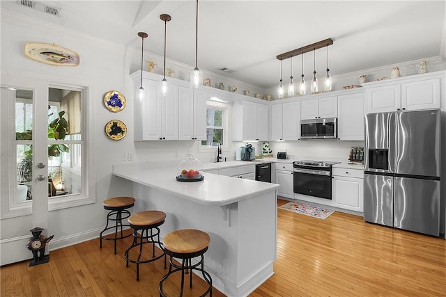 kitchen featuring stainless steel appliances, white cabinetry, kitchen peninsula, and decorative light fixtures