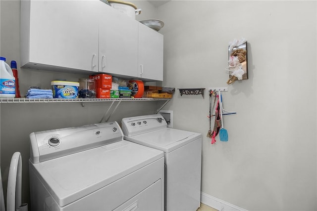 clothes washing area featuring cabinets and washer and clothes dryer