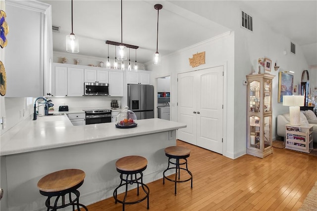 kitchen with pendant lighting, a breakfast bar area, stainless steel appliances, white cabinets, and kitchen peninsula