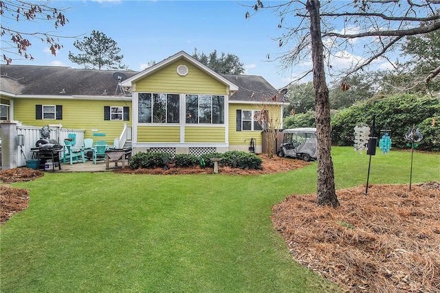 back of house with a sunroom and a lawn