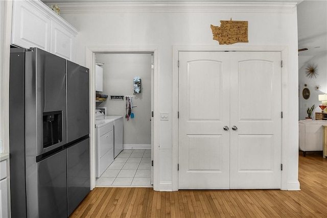 kitchen with light wood-type flooring, white cabinets, ornamental molding, stainless steel refrigerator with ice dispenser, and washer and clothes dryer