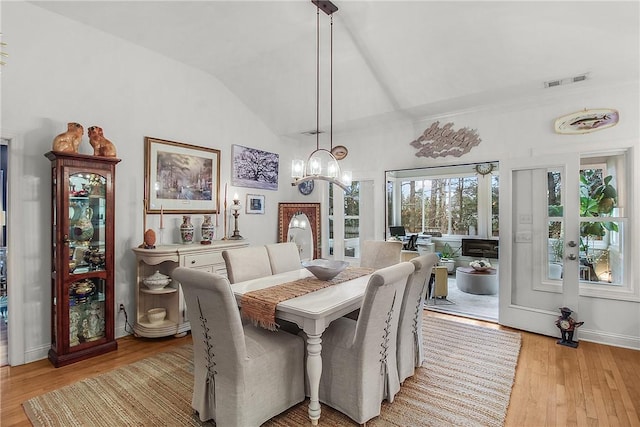 dining space with lofted ceiling, a chandelier, and light hardwood / wood-style flooring