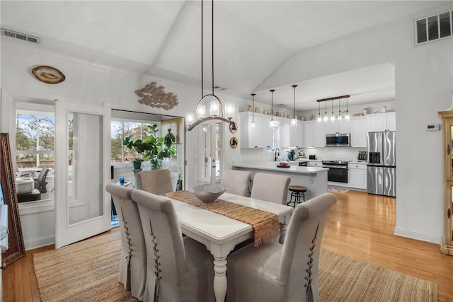 dining space featuring lofted ceiling, sink, and light wood-type flooring