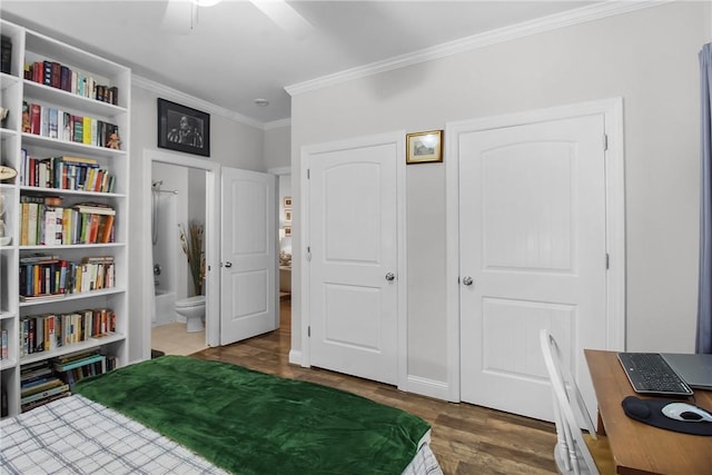 bedroom featuring crown molding, dark wood-type flooring, and ensuite bath