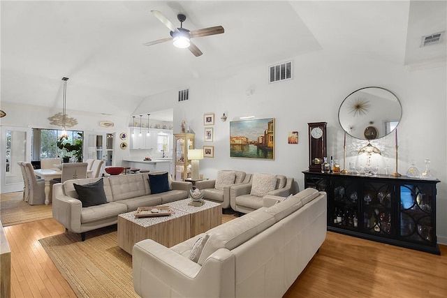 living room with ceiling fan, high vaulted ceiling, and light hardwood / wood-style flooring