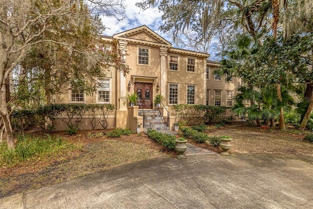 greek revival inspired property featuring french doors and stucco siding