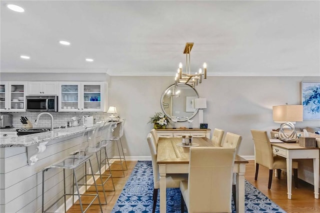 dining room with hardwood / wood-style floors, a notable chandelier, and ornamental molding