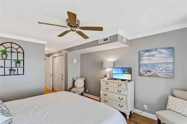 bedroom with a closet, ceiling fan, crown molding, and hardwood / wood-style flooring