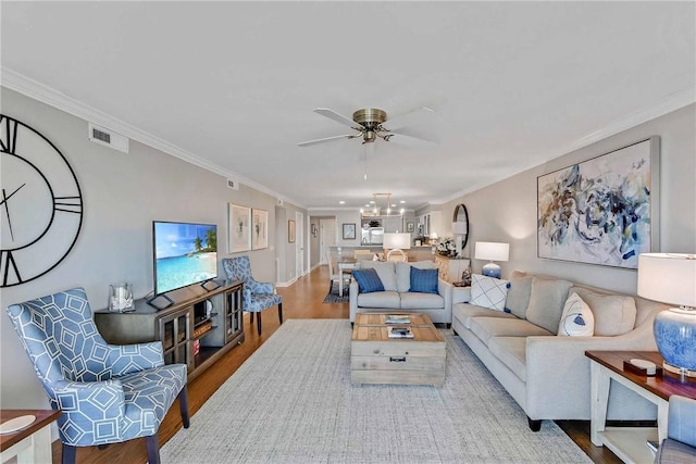 living room featuring crown molding, ceiling fan with notable chandelier, and hardwood / wood-style flooring