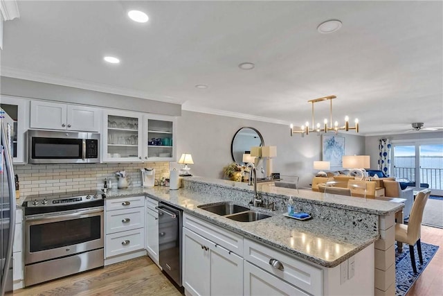 kitchen featuring kitchen peninsula, appliances with stainless steel finishes, white cabinets, and sink