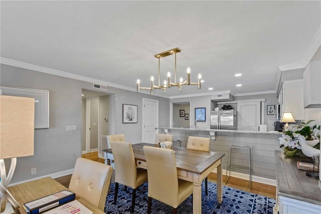 dining space with hardwood / wood-style floors, crown molding, and an inviting chandelier