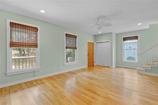 empty room with ceiling fan, a wealth of natural light, and light hardwood / wood-style flooring