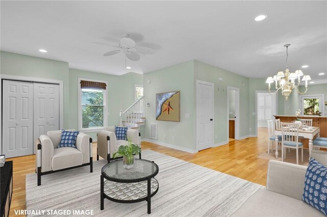 living room featuring light hardwood / wood-style flooring and ceiling fan with notable chandelier