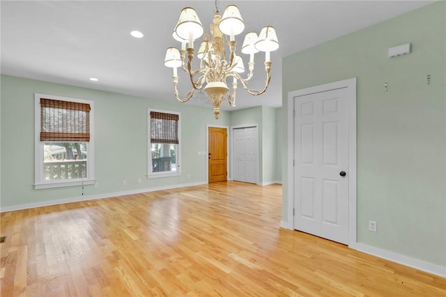 empty room with light hardwood / wood-style flooring and a chandelier