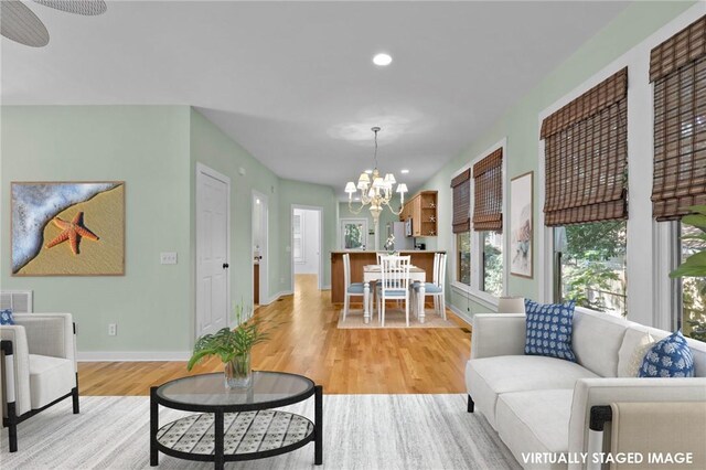 living room featuring ceiling fan with notable chandelier and light hardwood / wood-style floors