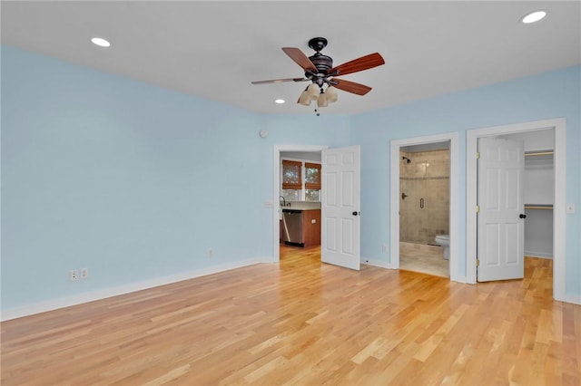 unfurnished bedroom with a walk in closet, ceiling fan, light wood-type flooring, connected bathroom, and a closet