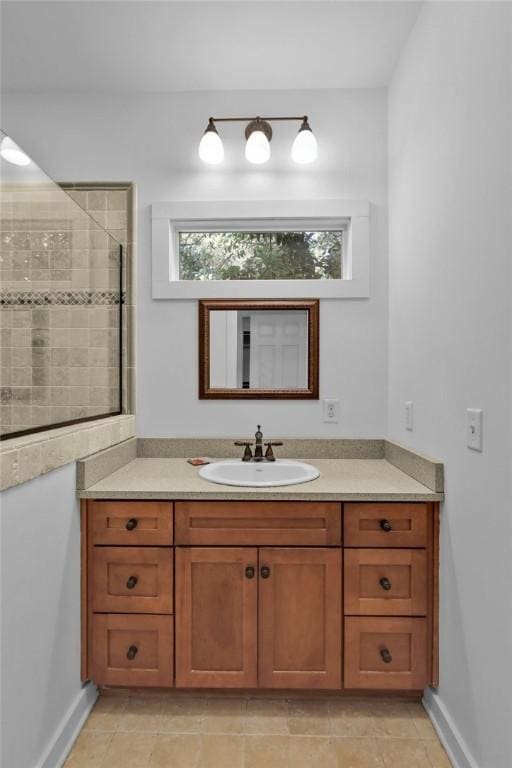 bathroom featuring tile patterned flooring, a tile shower, and vanity