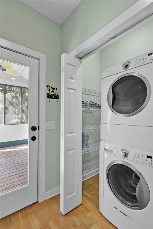 laundry area with light hardwood / wood-style flooring and stacked washer and clothes dryer