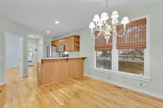 kitchen with pendant lighting, light hardwood / wood-style flooring, appliances with stainless steel finishes, kitchen peninsula, and a chandelier