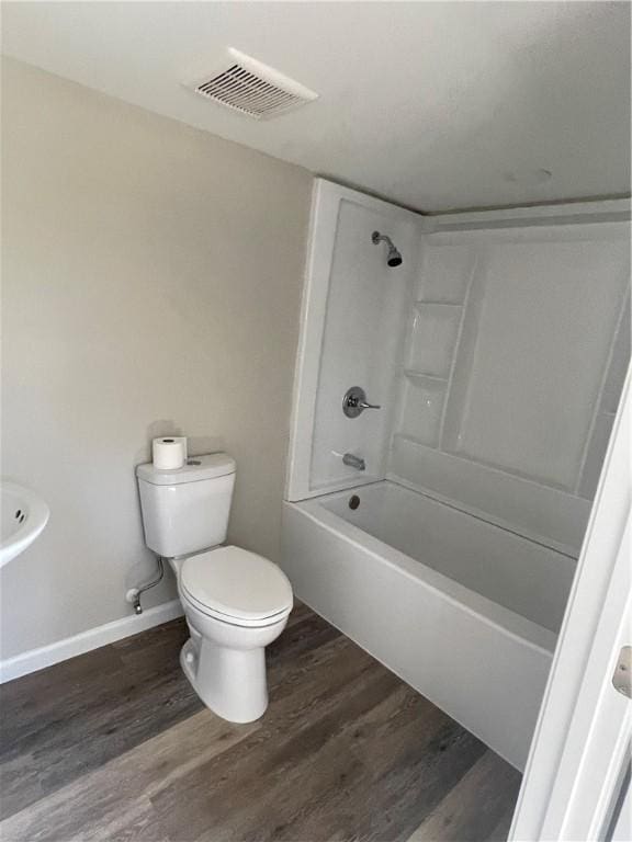 bathroom with visible vents, toilet, wood finished floors, baseboards, and shower / bathtub combination