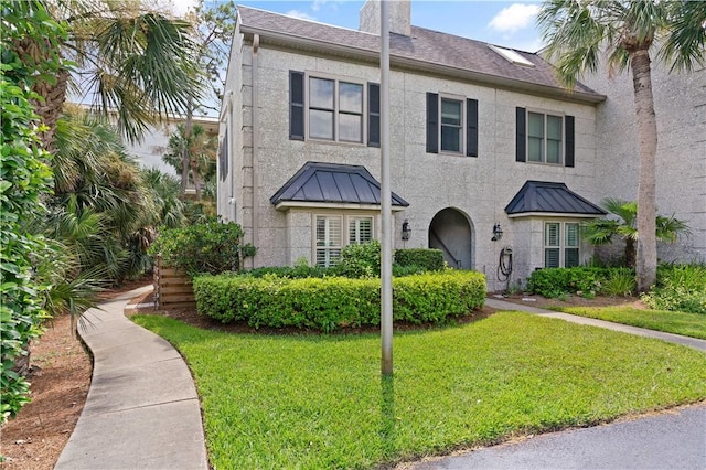 1035 Beachview Dr Unit 301, Saint Simons Island, GA 31522 - view of property featuring stucco siding, a front yard, a chimney, and a standing seam roof