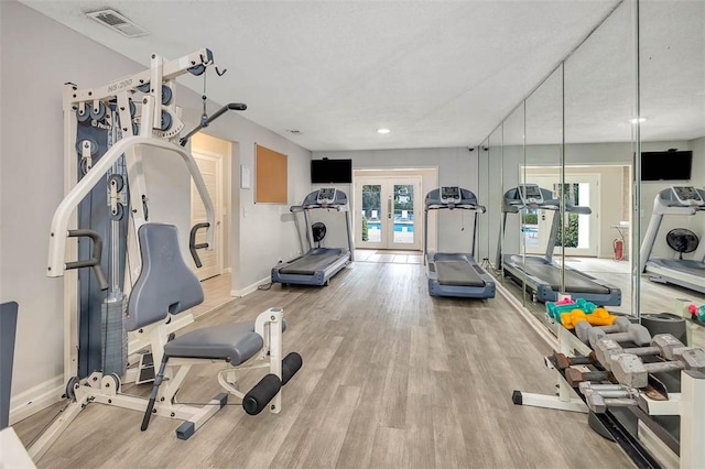 gym with light hardwood / wood-style flooring and french doors