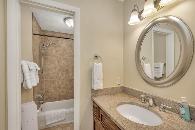 bathroom with vanity, a textured ceiling, and tiled shower / bath