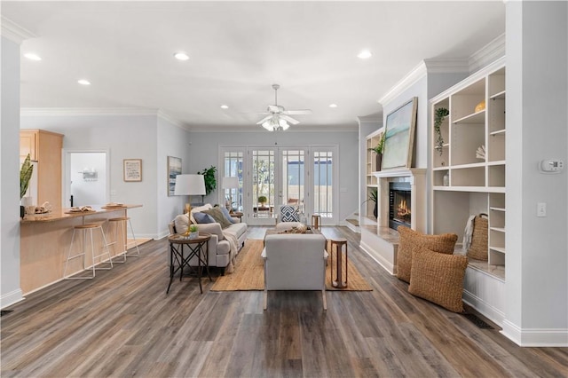 living room featuring dark hardwood / wood-style flooring, french doors, built in features, ornamental molding, and ceiling fan