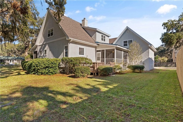 back of property featuring a wooden deck, a yard, and a sunroom