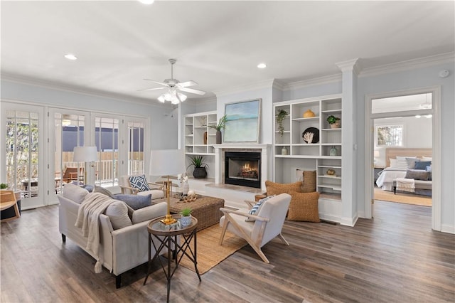 living room featuring dark wood-type flooring, ceiling fan, a wealth of natural light, and crown molding