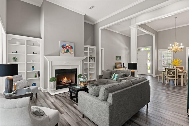 living area featuring crown molding, visible vents, an inviting chandelier, and wood finished floors
