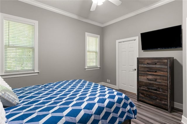bedroom featuring crown molding, baseboards, wood finished floors, and multiple windows