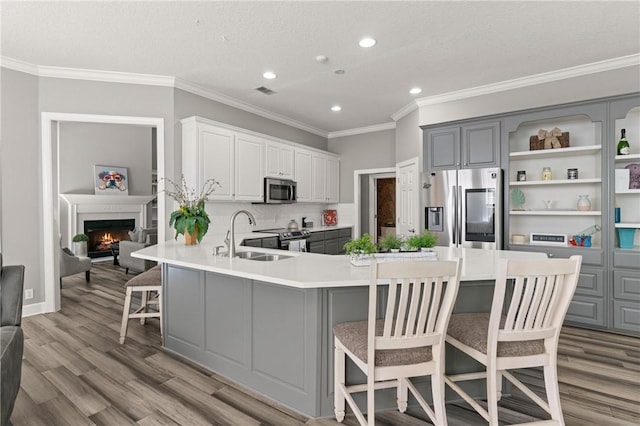kitchen featuring gray cabinets, wood finished floors, a sink, stainless steel appliances, and recessed lighting