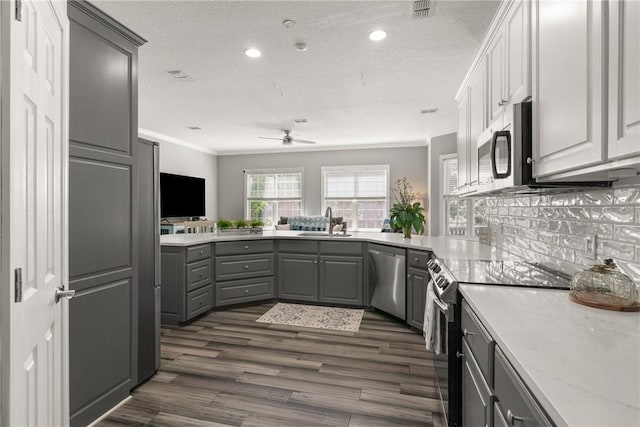kitchen featuring ceiling fan, appliances with stainless steel finishes, a sink, gray cabinetry, and ornamental molding