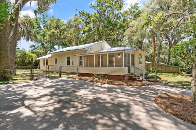 315 Pine St, Saint Simons Island, GA 31522 - view of front of home with a gate, a sunroom, entry steps, a metal roof, and view of scattered trees