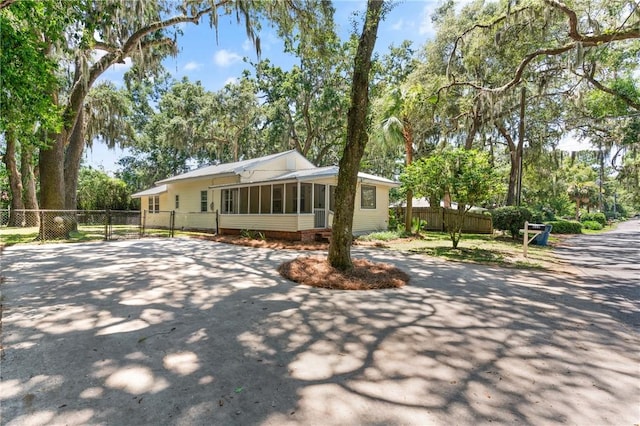315 Pine St, Saint Simons Island, GA 31522 - back of property featuring a sunroom, driveway, and view of wooded area