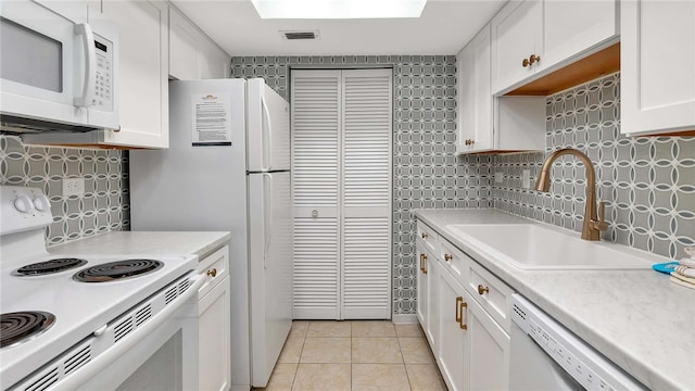 kitchen with white appliances, sink, light tile patterned floors, tasteful backsplash, and white cabinetry