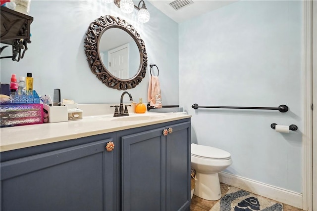 bathroom featuring toilet, vanity, visible vents, and baseboards