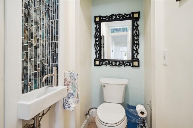 bathroom with toilet, baseboards, and a sink