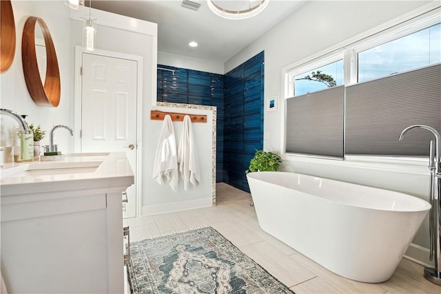 full bath with baseboards, visible vents, a freestanding bath, and vanity