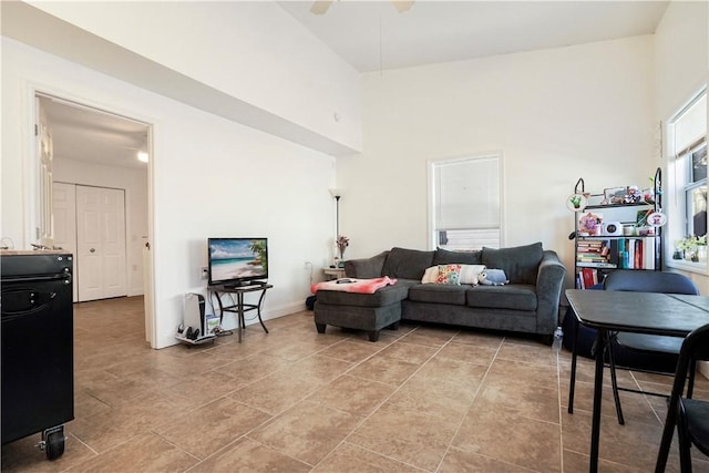 living room featuring a ceiling fan, a towering ceiling, and light tile patterned floors