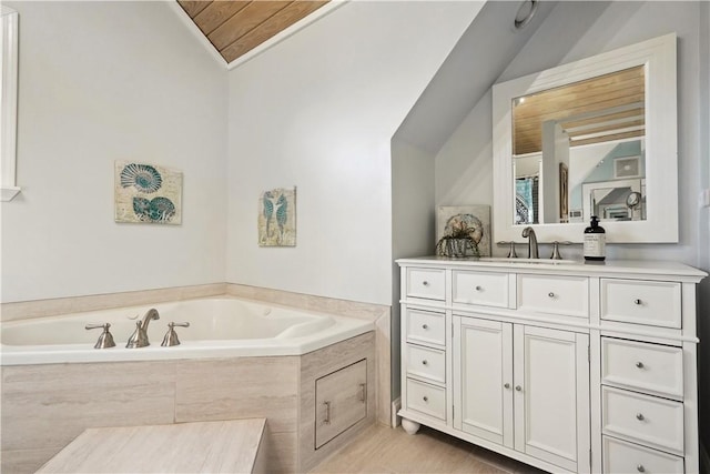 bathroom featuring lofted ceiling, a garden tub, and vanity