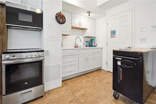 kitchen featuring light tile patterned floors, butcher block counters, appliances with stainless steel finishes, white cabinetry, and a sink