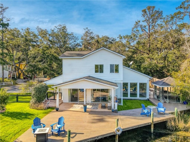 rear view of property featuring a lawn and fence