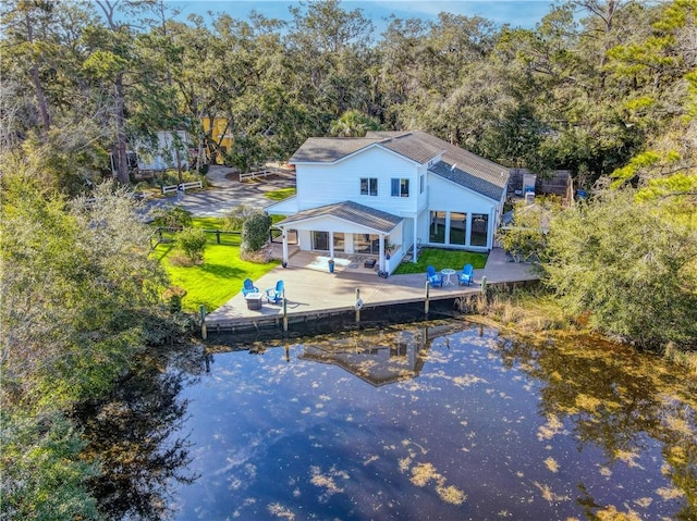 back of property featuring a water view, a patio area, driveway, and fence