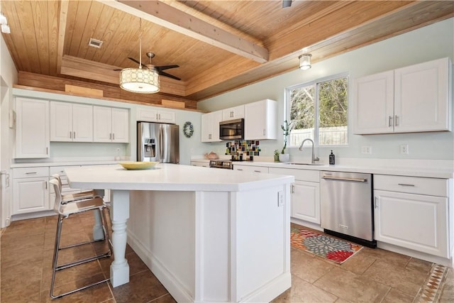 kitchen featuring white cabinets, appliances with stainless steel finishes, light countertops, and a center island