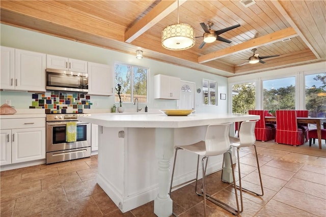 kitchen with white cabinets, wood ceiling, a center island, stainless steel appliances, and light countertops